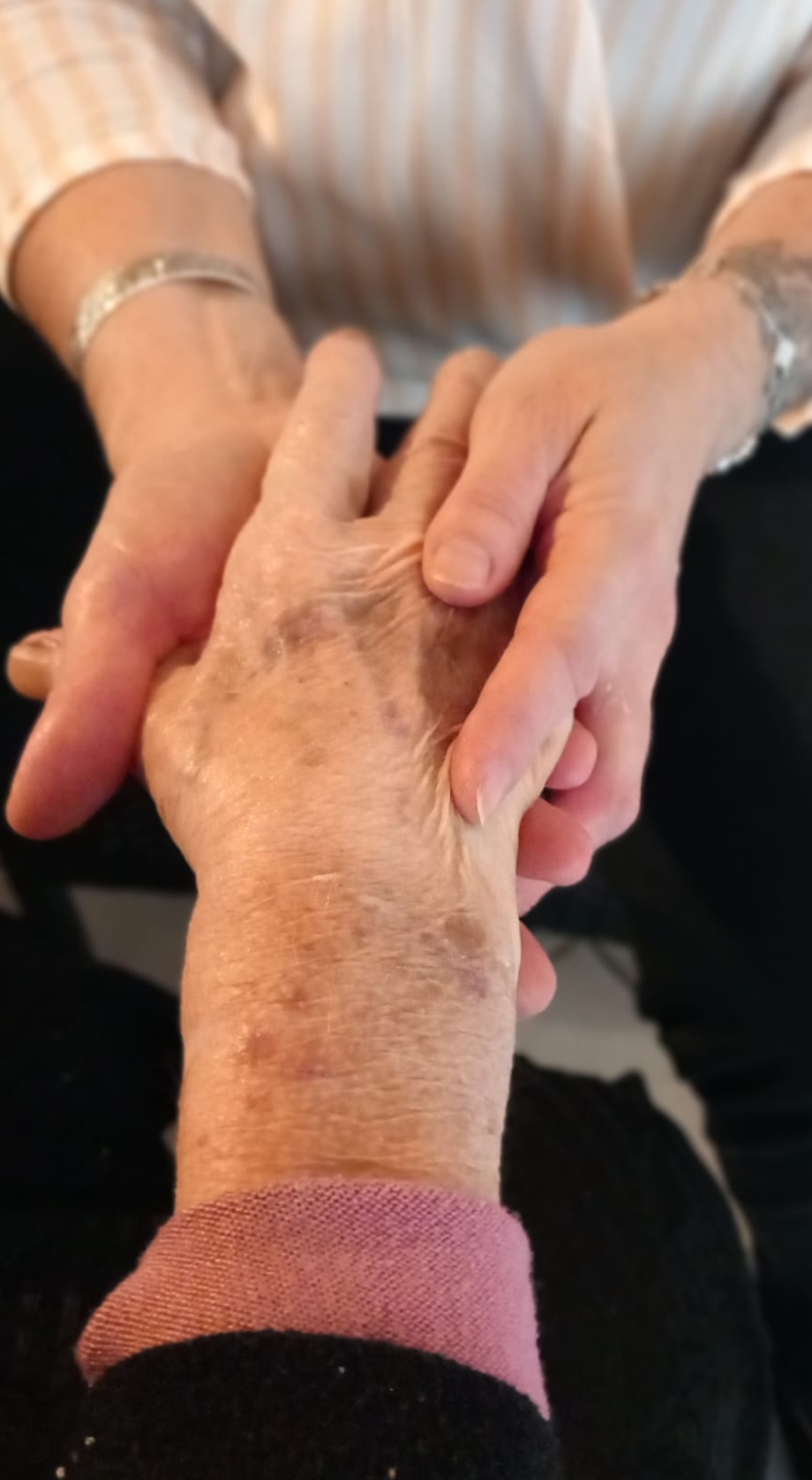 Une main âgée tenue avec soin et tendresse.